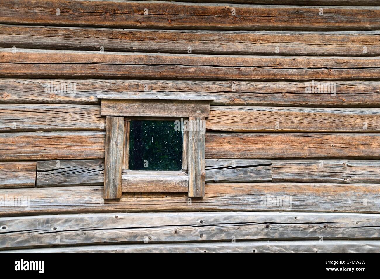 Une petite fenêtre sale on a rustic log mur Banque D'Images