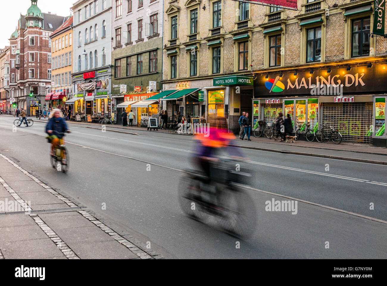 Les cyclistes équitation passé en vitesse le long d'une rue à Copenhague pendant le trajet de retour en soirée. Banque D'Images