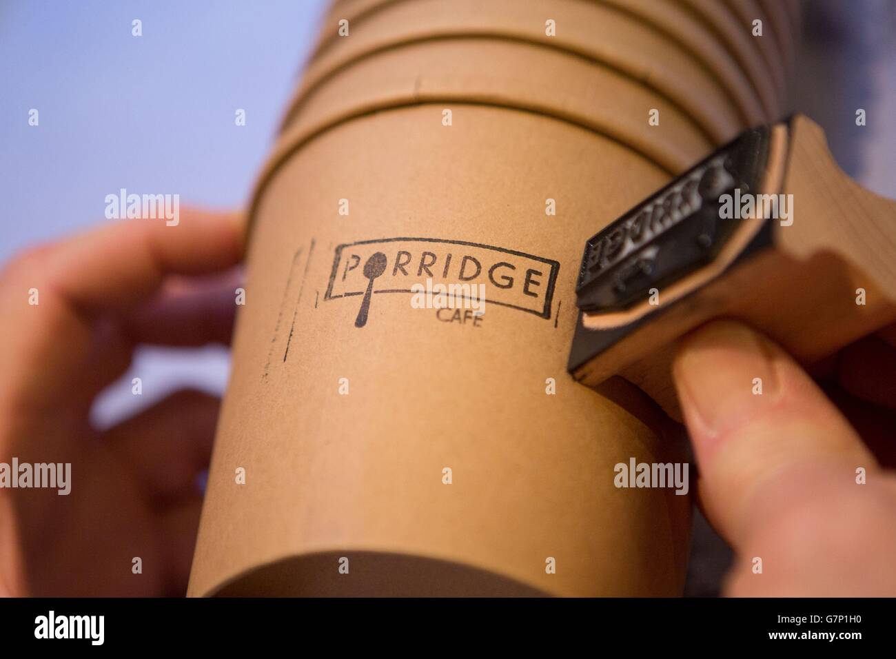 Lancement du café porridge - Londres.Un ouvrier appose le logo sur une tasse de porridge au café de porridge à Shoreditch, Londres. Banque D'Images