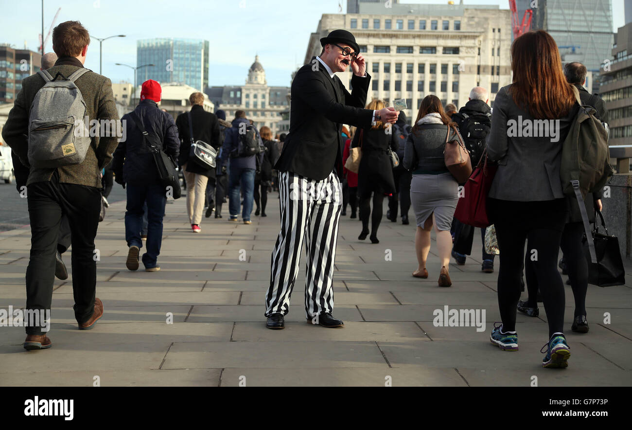 Un acteur, habillé comme un fisc, met les mains libres et livre;5 notes sur le London Bridge pour illustrer une étude de Santander qui montre que les Britanniques distribuent chaque année 57 millions de livres sterling au fisc inutilement en ne profitant pas de l'épargne libre d'impôt. Banque D'Images