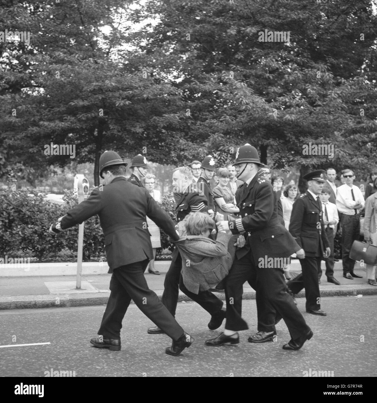 La police a emportant un manifestant de la guerre du Vietnam à Grosvenor Square à la suite d'une réunion du Parti communiste à Trafalgar Square à Londres, où elle s'était réunie pour protester contre « l'agression américaine au Vietnam ».La réunion a condamné les bombardements américains de Hanoï et Haiphong.Après la réunion, une manifestation a eu lieu à l'ambassade des États-Unis. Banque D'Images