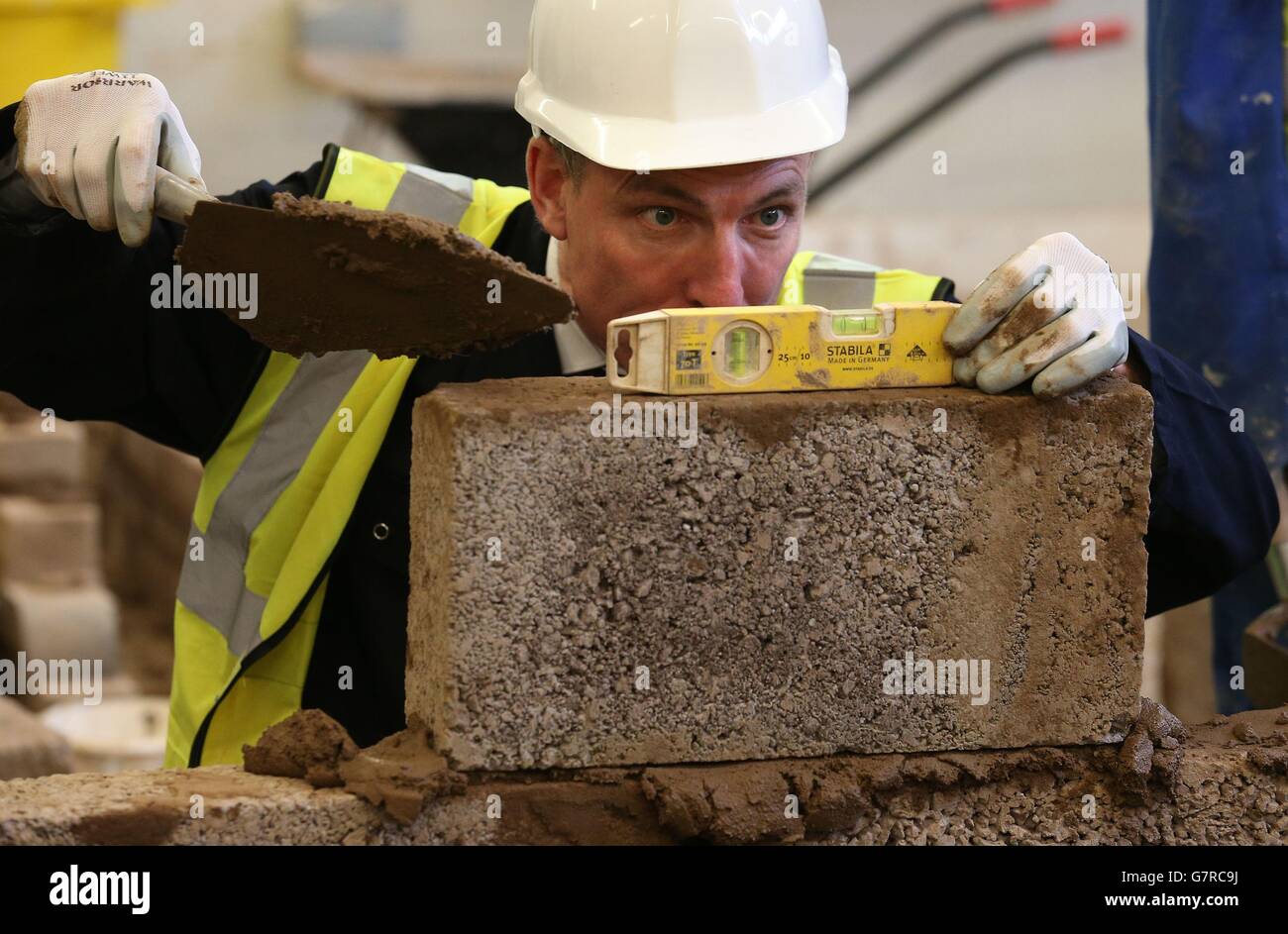 Le chef travailliste écossais Jim Murphy tente sa main sur la pose de briques alors qu'il visite un atelier de briquetage au New College Lanarkshire, près de Motherwell. Banque D'Images