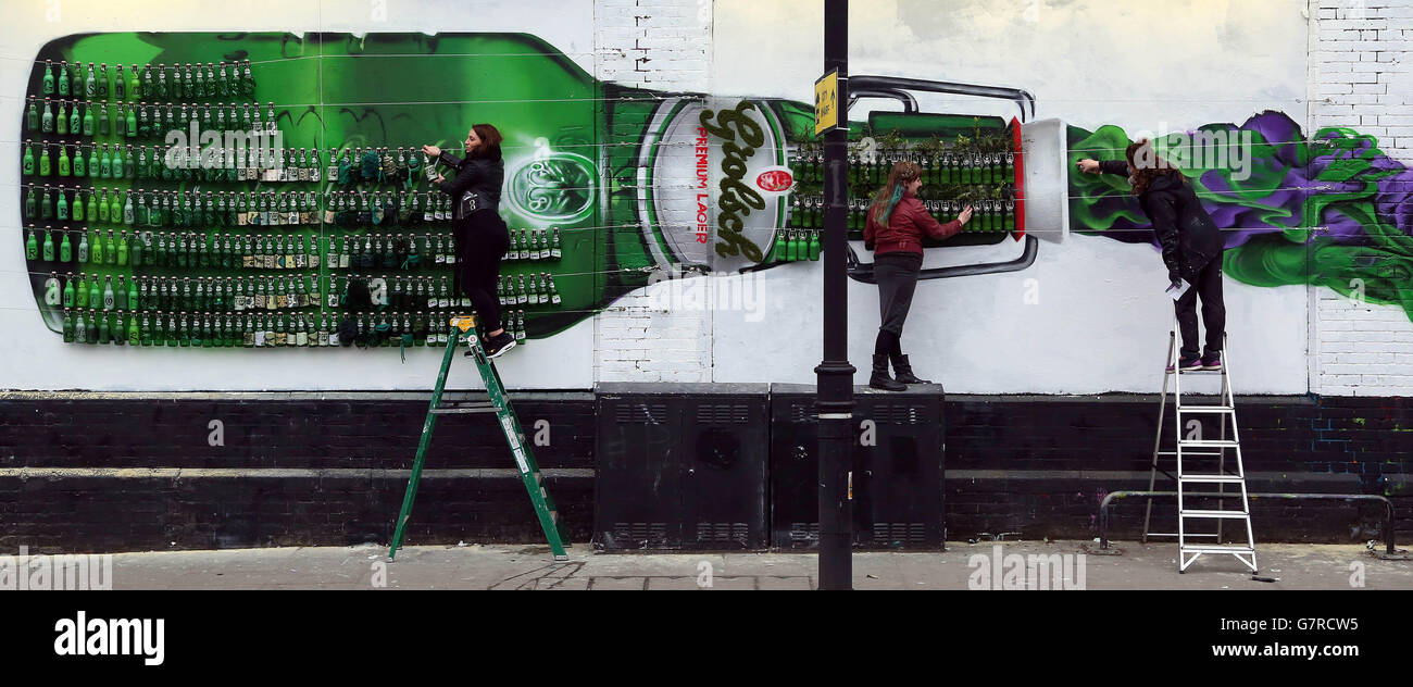 Premier pageur hollandais, Grolsch célèbre son 400e anniversaire avec un hommage géant à la célèbre bouteille swing top de la boisson, en partenariat avec (de gauche à droite) Alexia James, Lisa Campbell-Bannerman et Rosie Woods, du collectif d'art Graffiti Life, sur le mur d'art Shoreditch à l'est de Londres. Banque D'Images