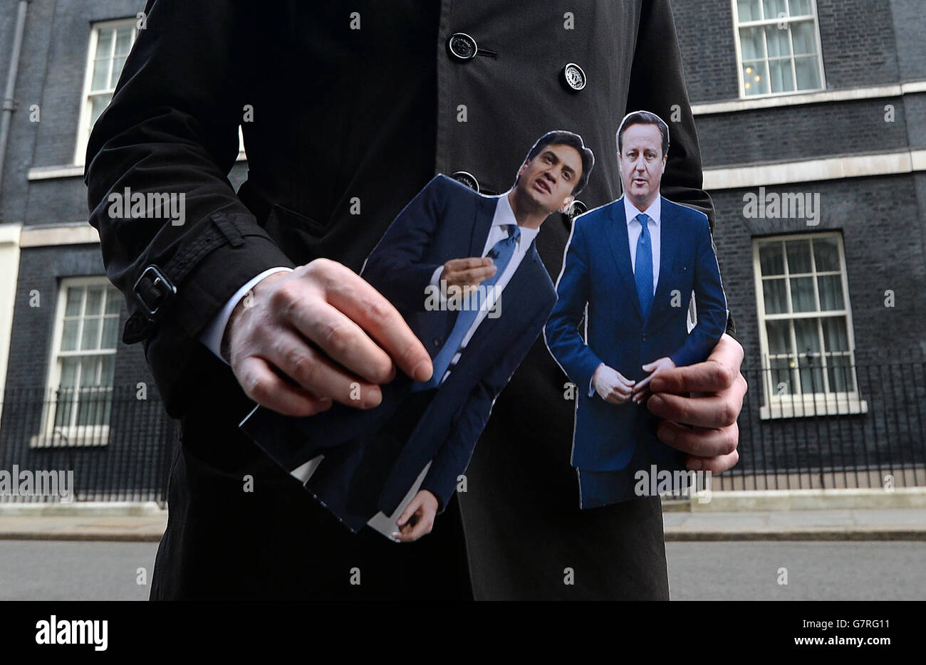Un journaliste à la télévision tient des coupures de presse du Premier ministre David Cameron et du leader travailliste Ed Miliband à Downing Street, Londres, avant que le ministre George Osborne ne présente le budget annuel. Banque D'Images