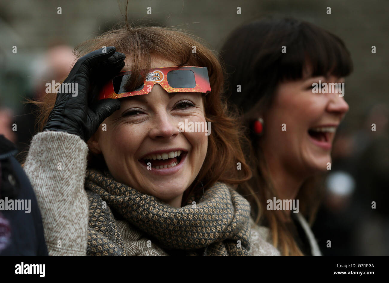 Les gens regardent alors qu'ils attendent une pause dans les nuages pour apercevoir l'éclipse partielle du soleil depuis la place principale de Trinity College de Dublin, en Irlande. Banque D'Images