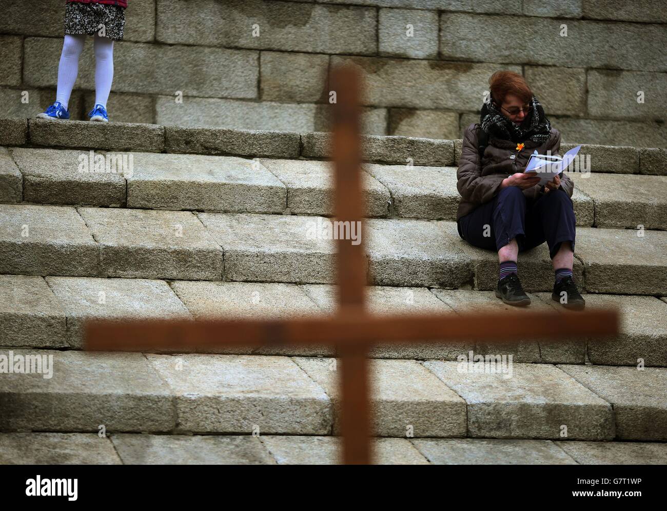 Une femme lit son livret de masse tout en étant assise sur les marches du monument Wellington lors de la procession annuelle du « chemin de la croix » du Monument Wellington à la Croix papale dans le Phoenix Park, Dublin. Banque D'Images