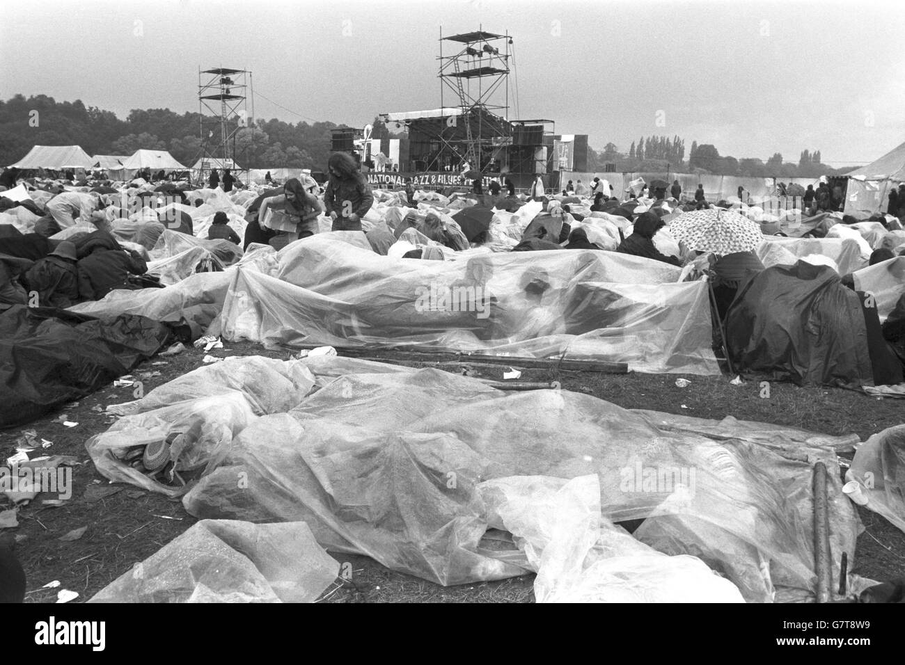 Les fans se rassemblent sous des draps en plastique tandis que la pluie déverse sur la foule estimée à 30,000 60 hectares qui a emballé le site du festival de la pop, à côté de la Tamise à Reading.Le festival a duré 3 jours. Banque D'Images