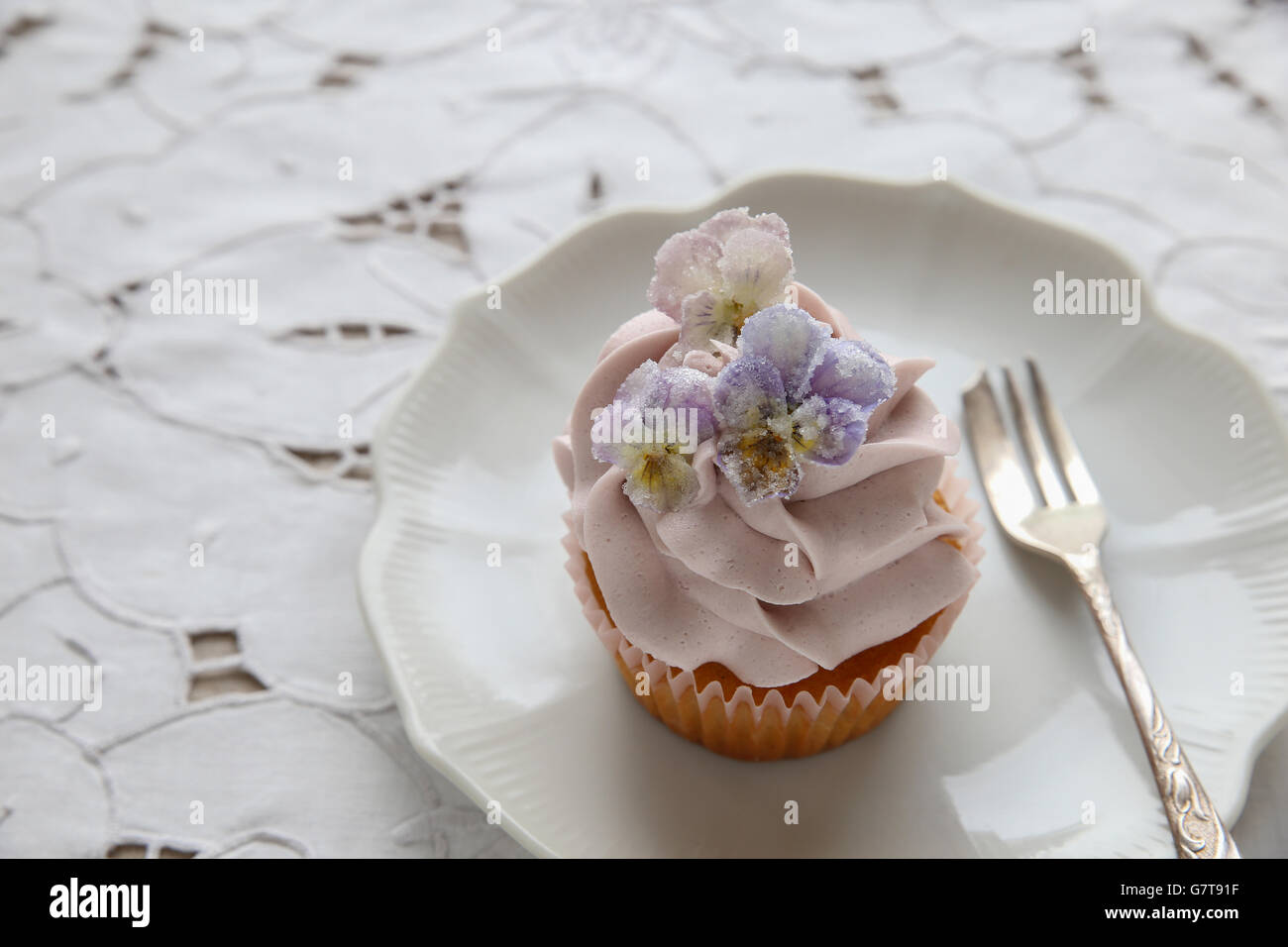 Cupcakes avec violet fleurs comestibles sucrées sur plaque vintage Banque D'Images