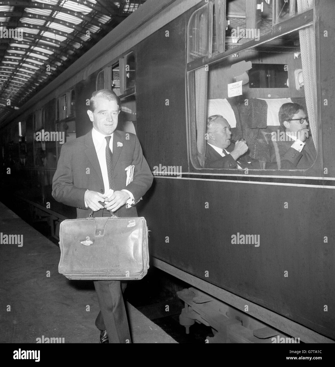 Christopher Chataway, sous-secrétaire d'État parlementaire mixte du ministère de l'éducation et des Sciences, va monter à bord d'un train à la gare de Paddington à Londres. Le chef du Parti travailliste Harold Wilson peut être vu à bord du train, en train de partir pour Cardiff pour commencer sa tournée électorale générale. Banque D'Images