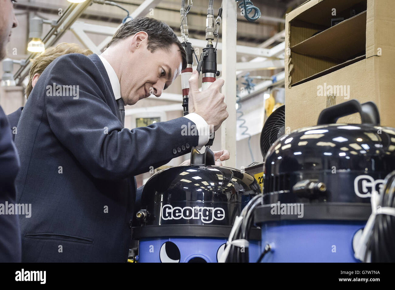 Le chancelier de l'Échiquier George Osborne fixe la poignée sur l'un des trois vaccins spéciaux de couleur bleue « George » lors de sa visite à l'usine de Numatic qui fabrique la célèbre marque de vaccins « Henry » à Chard, dans le Somerset. Banque D'Images