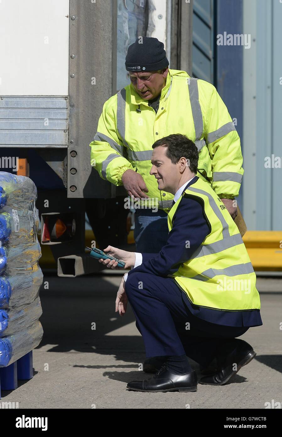Le chancelier George Osborne (à genoux) scanne une charge prête à être distribuée avec le superviseur Mick Shergold lors d'une visite à William West distribution Ltd à Ilkeston, dans le Derbyshire. Banque D'Images