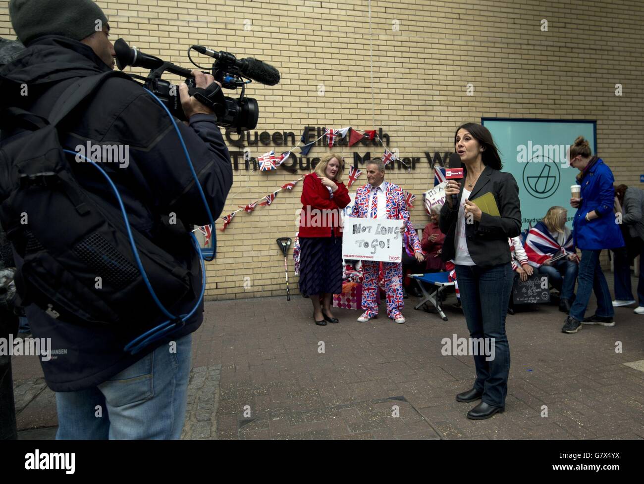 Un journaliste de la chaîne italienne Rai News24 parle à la caméra devant le Lindo Windo de l'hôpital St Mary's de Paddington, Londres, alors que l'attente de l'arrivée du duc et de la duchesse du deuxième enfant de Cambridge continue. Les fans royaux (dont Terry Hutt, centre, qui célèbre aujourd'hui son 80e anniversaire), les médias et le public attendent des nouvelles de la naissance à l'extérieur de l'hôpital. Banque D'Images