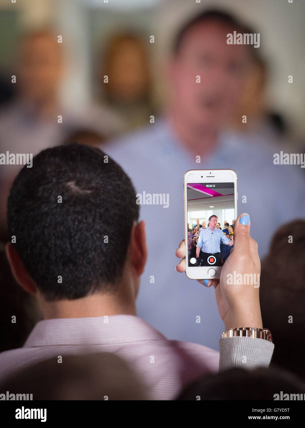 La foule prend des photos sur son téléphone portable tandis que le Premier ministre David Cameron prononce un discours lors de sa visite dans un entrepôt de services publics pendant la campagne électorale générale. Banque D'Images