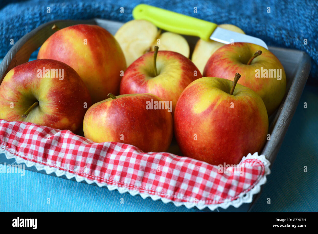 Close up de rouge, jaune, vert pommes dans bol en bois avec couteau et tranches de pomme rouge blanc campagne nostalgique napperon damier Banque D'Images