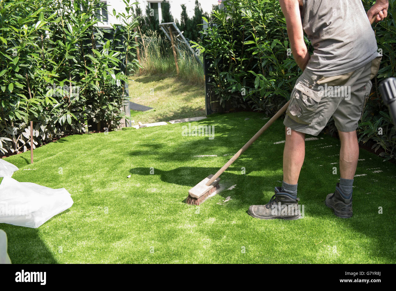 Jardinier professionnel met du sable sur le gazon synthétique Banque D'Images