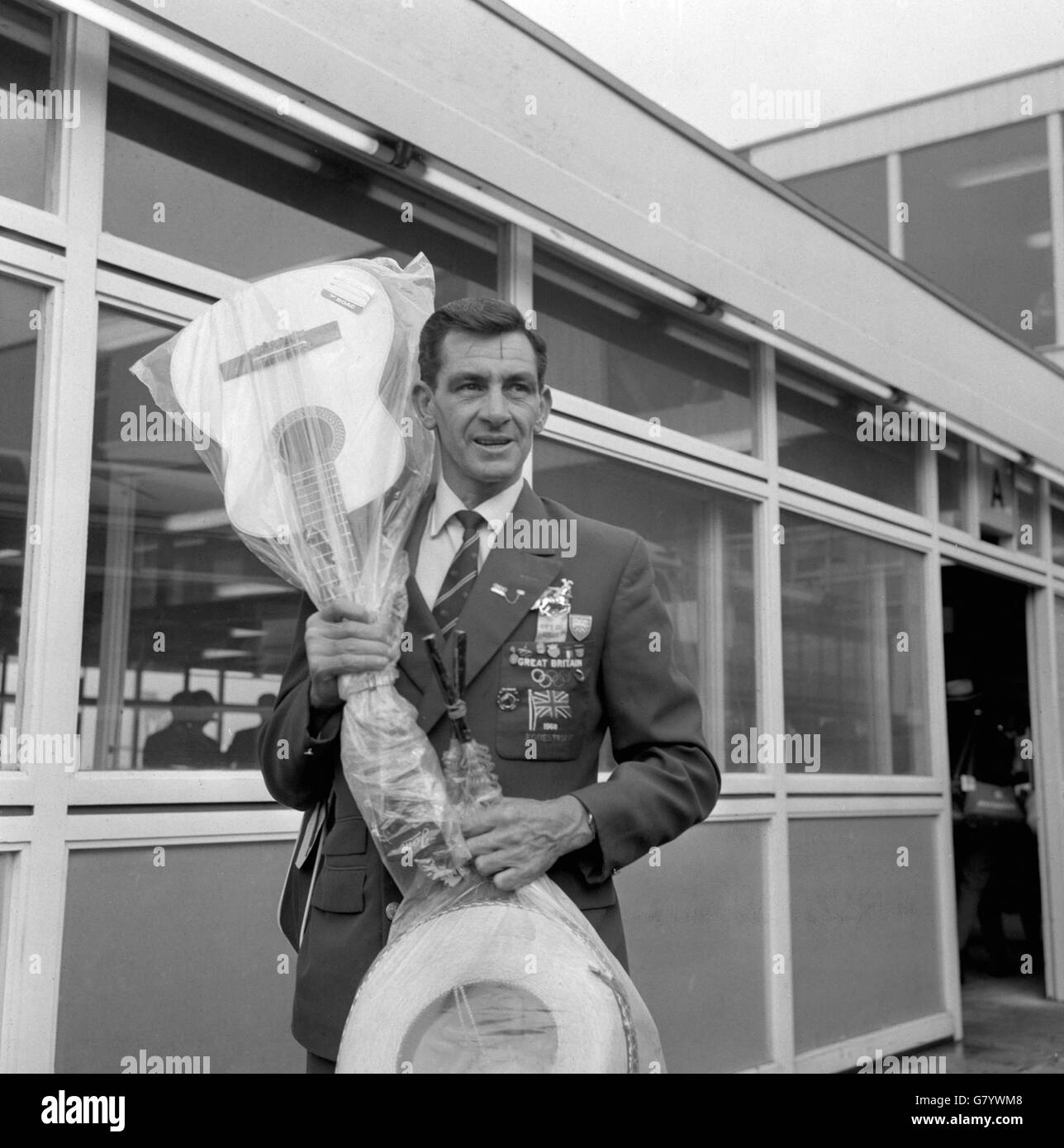 Le sergent d'état-major Ben Jones, membre de l'équipe équestre olympique britannique, qui a remporté une médaille d'or aux Jeux olympiques au Mexique, à son retour à l'aéroport d'Heathrow, à Londres. Ben a également apporté quelques souvenirs - une guitare et un sombrero. Banque D'Images