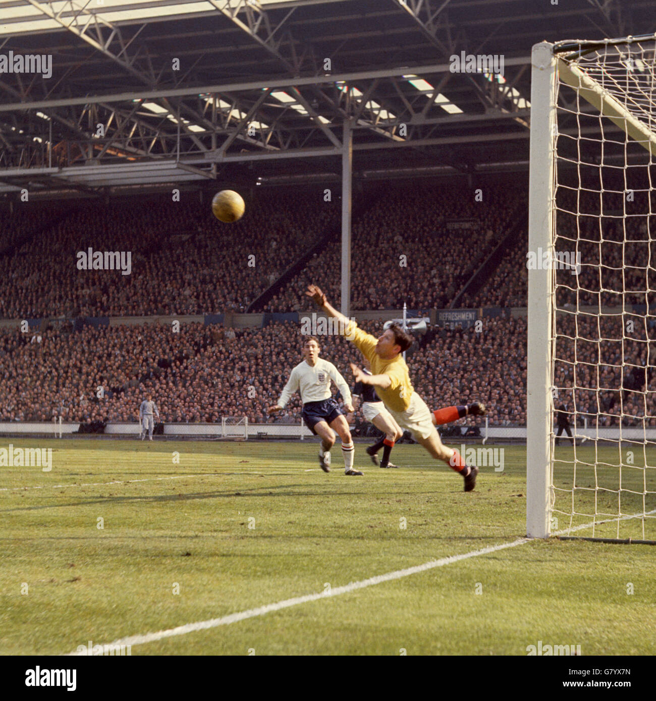 Football - Home Championnat International - Angleterre / Ecosse - Wembley Stadium.Bill Brown, gardien de but écossais, fait une économie, sous la surveillance de Jimmy Greaves, de l'Angleterre. Banque D'Images