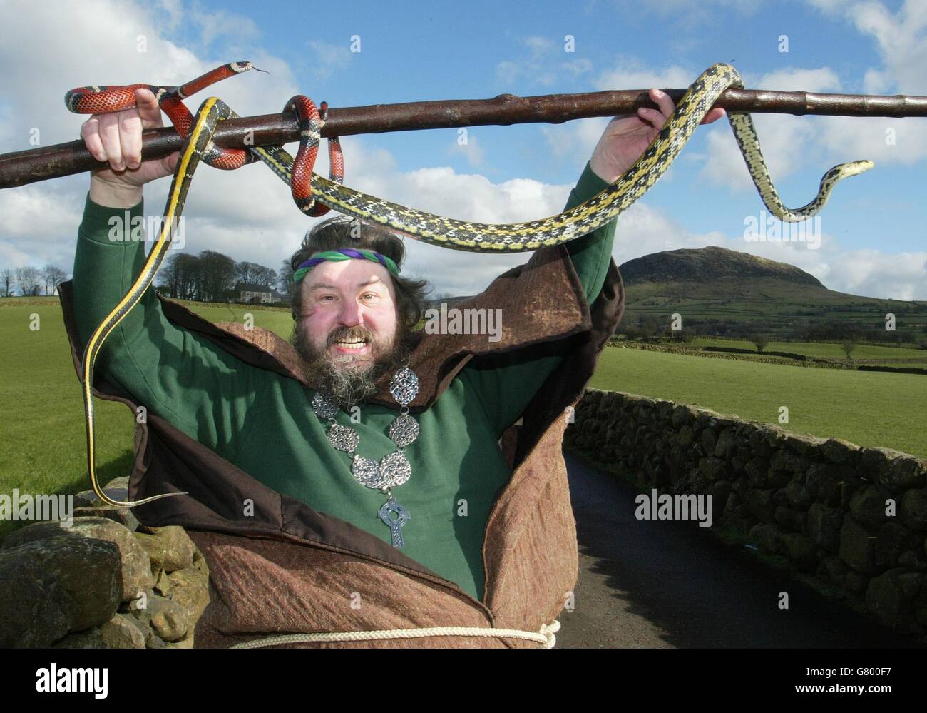 Lynn Corry aka St Patrick, et ses amis de serpent chutent près de Slemish Mountain, au nom de l'Office du tourisme d'Irlande du Nord, pour vous rappeler qu'il y a beaucoup de grands événements de la St Patrick dans toute l'Irlande du Nord. Avec de nombreuses entreprises et écoles fermées pour le jour férié, des dizaines de milliers se préparaient à célébrer. Vingt mille personnes étaient attendues à Downpatrick - où St Patrick est réputé être enterré - pour le plus grand carnaval intercommunautaire de la province. Banque D'Images
