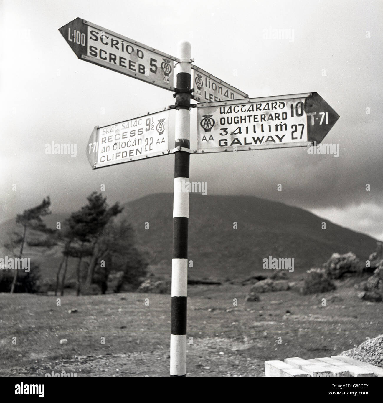 Dans les années 1950, panneaux de signalisation historique et directionnel dans la campagne ouest de l'Irlande, à la fois en langue irlandaise (gaélique) et en anglais. L'irlandais, communément appelé gaélique. Était la langue d'origine de l'Irlande et était la première langue utilisée dans le pays jusqu'à la fin du XVIIIe siècle. Banque D'Images