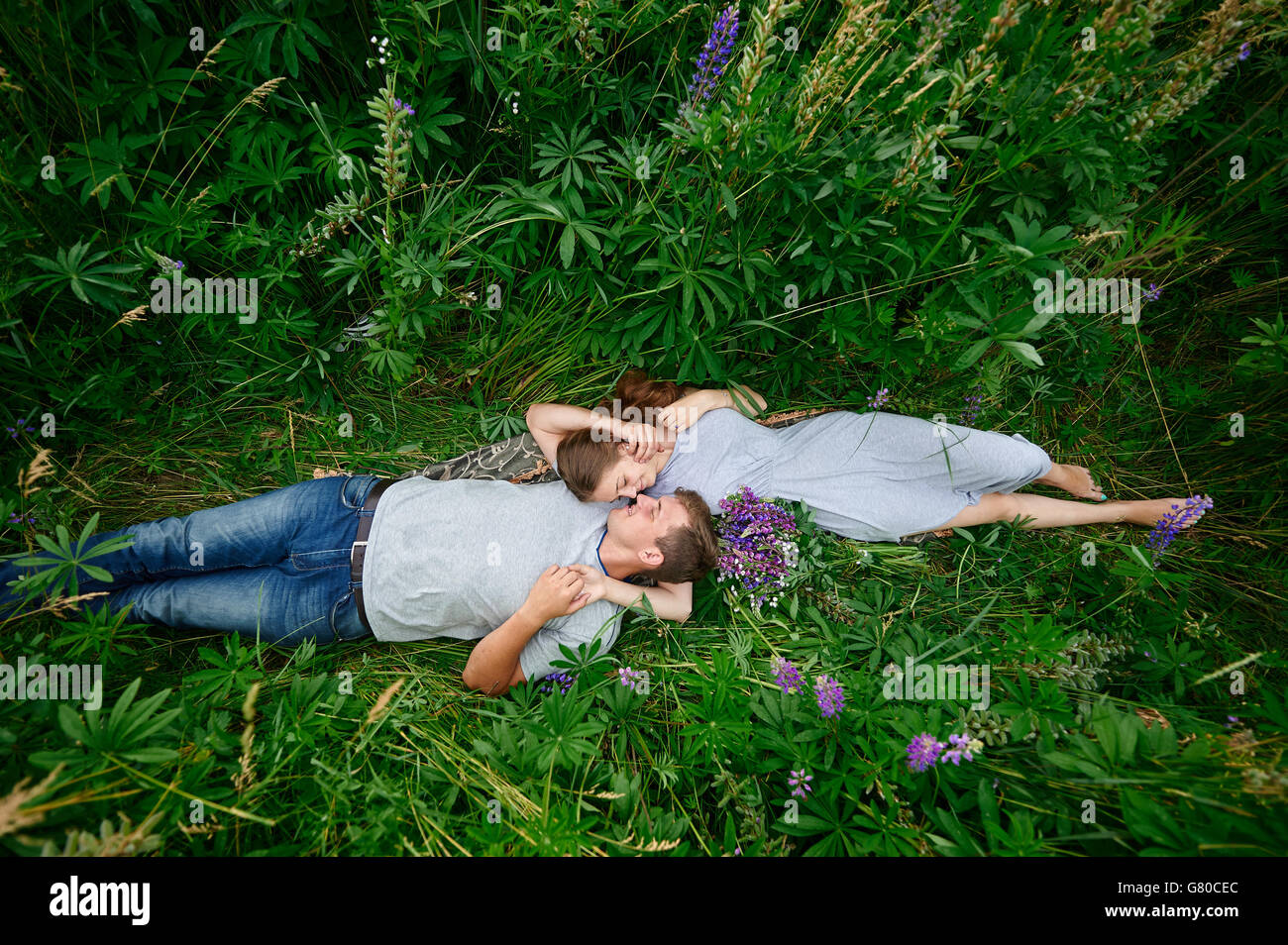 Beau couple heureux jeune homme et femme lying outdoors on Green grass Banque D'Images