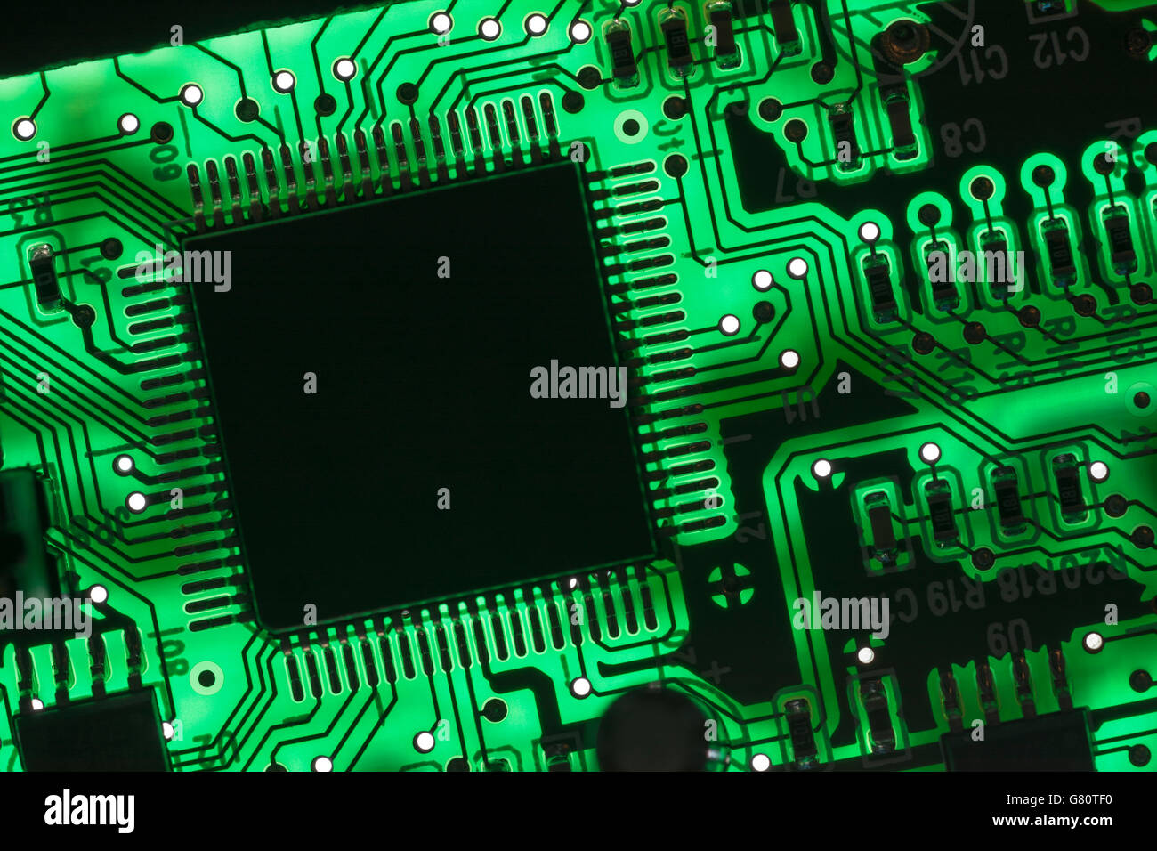 Concept de technologie informatique. Carte de circuit imprimé / carte de circuit imprimé montrant les composants rétroéclairés avec un voyant vert. Câblage à l'intérieur du calculateur, gros plan du circuit, électronique Banque D'Images