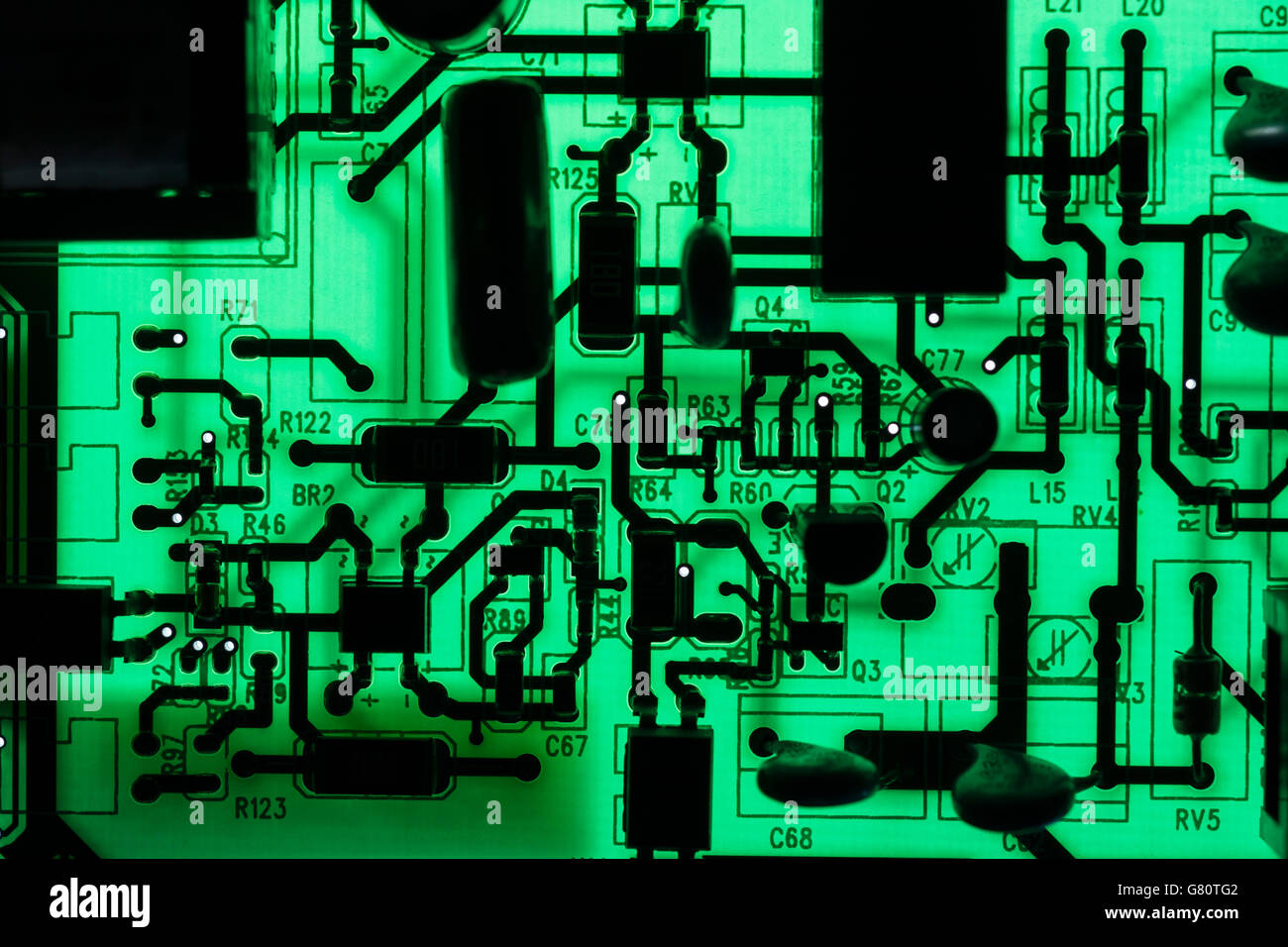 Concept de technologie informatique. Carte de circuit imprimé / carte de circuit imprimé montrant les composants rétroéclairés avec un voyant vert. Câblage à l'intérieur du calculateur, gros plan du circuit, électronique. Banque D'Images