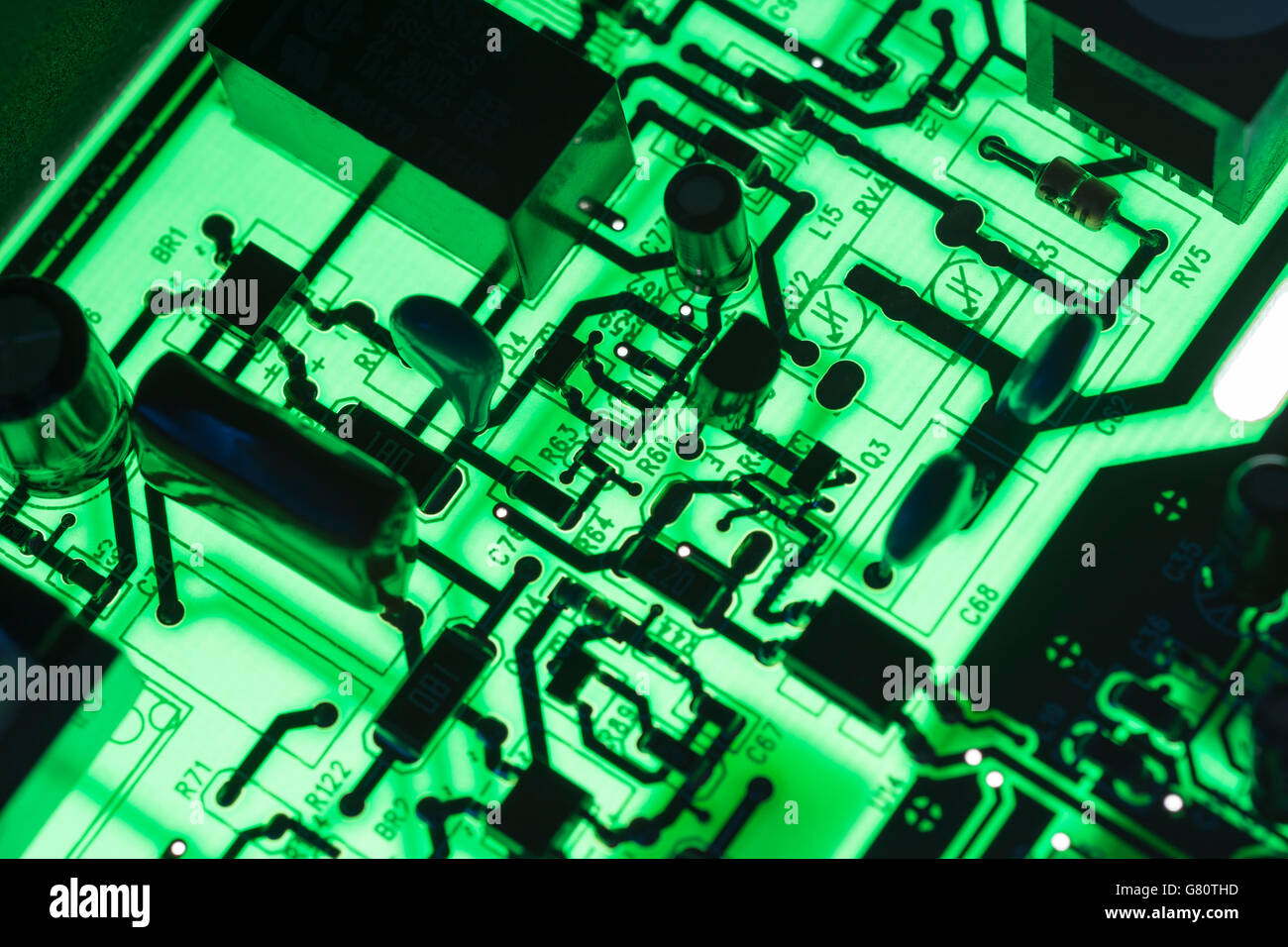 Concept de technologie informatique. Carte de circuit imprimé / carte de circuit imprimé montrant les composants rétroéclairés avec un voyant vert. Câblage à l'intérieur du calculateur, gros plan du circuit, électronique. Banque D'Images