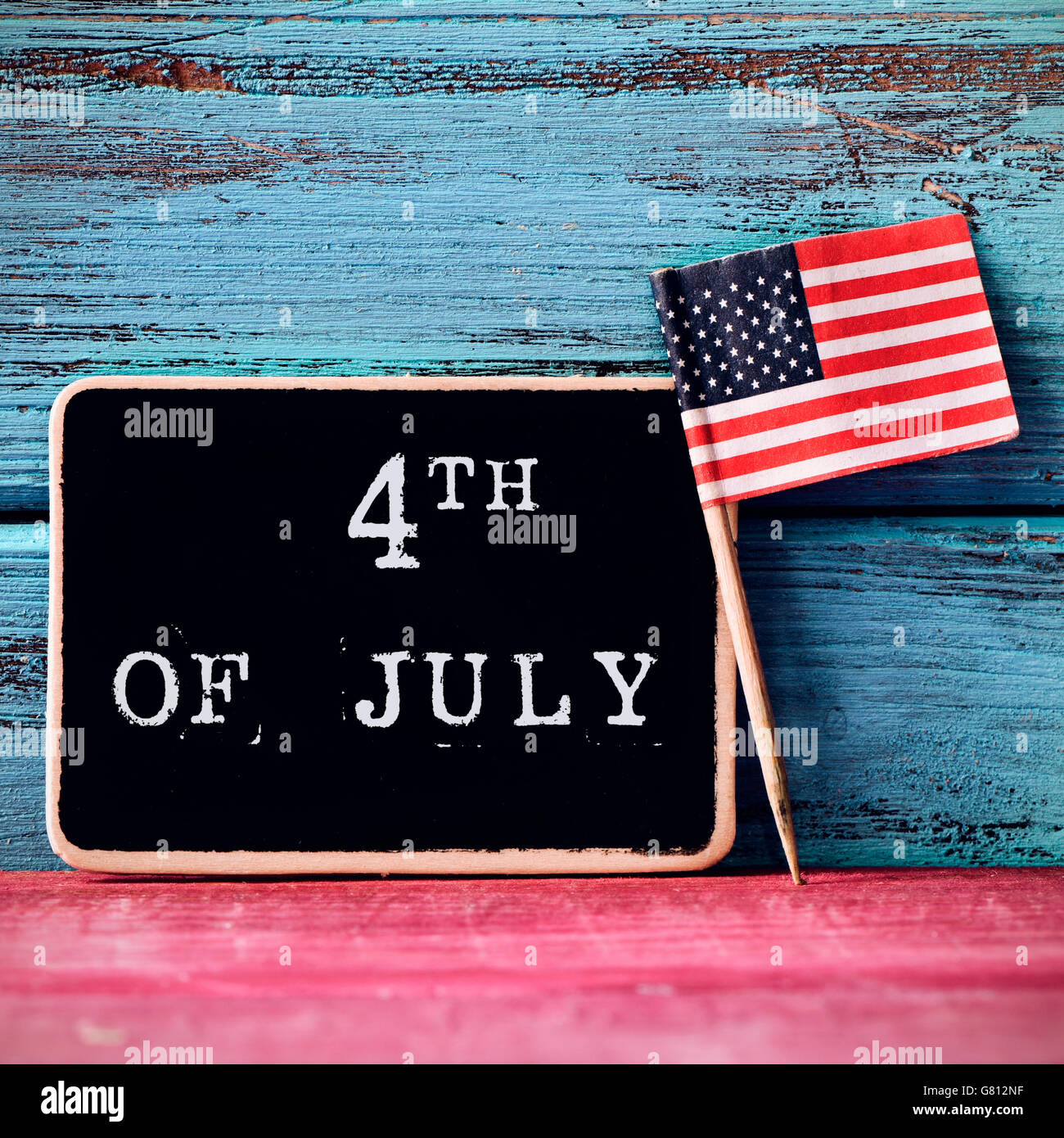 Un tableau sur le texte 4 juillet écrit en C et un drapeau des États-Unis, sur un fond de bois rouge et bleu Banque D'Images