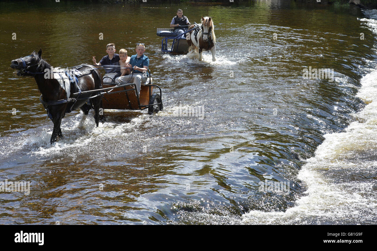 Les membres de la communauté itinérante prennent le cheval et les pièges dans la rivière Eden au début de la foire du cheval Appleby, le rassemblement annuel des gitans et des voyageurs à Appleby, Cumbria. Banque D'Images