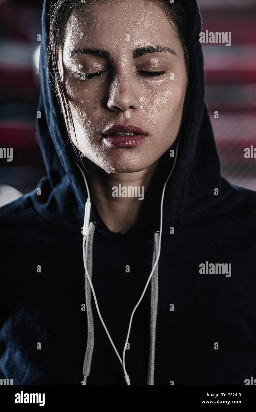 Woman in hooded shirt de sueur sur le visage à la salle de sport Banque D'Images