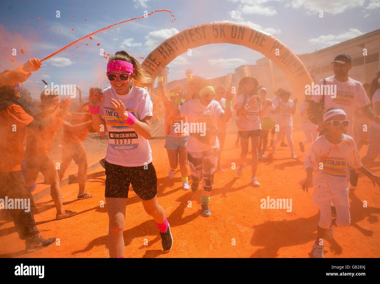 Les volontaires lancent de la poudre colorée sur les coureurs pendant la course de couleur au stade Wembley à Londres. Banque D'Images