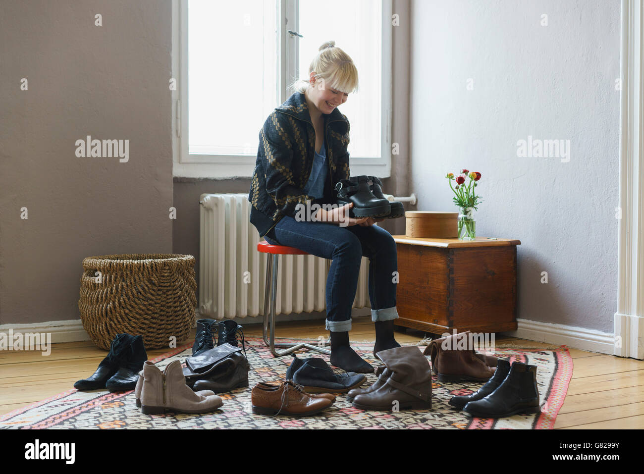 Happy woman holding shoes tout en restant assis à la maison Banque D'Images