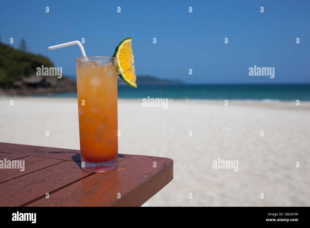 Verre de rafraîchissement sur table en bois à plage en journée ensoleillée Banque D'Images