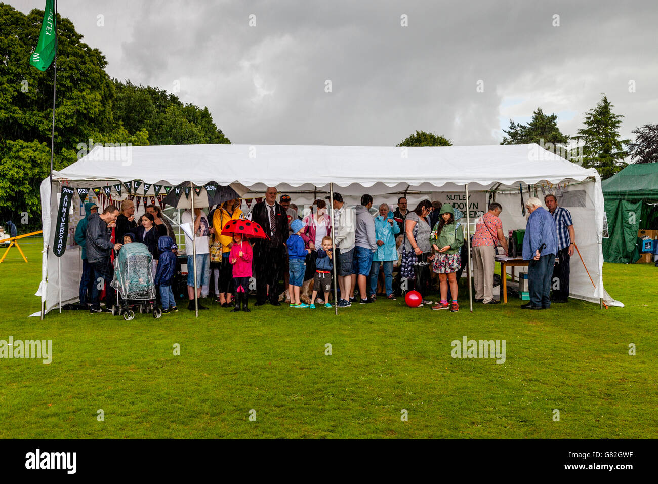 Les gens à l'abri de la pluie dans une tente à l'Assemblée annuelle de la fête de l'été dans le village de Nutley, East Sussex, UK Banque D'Images