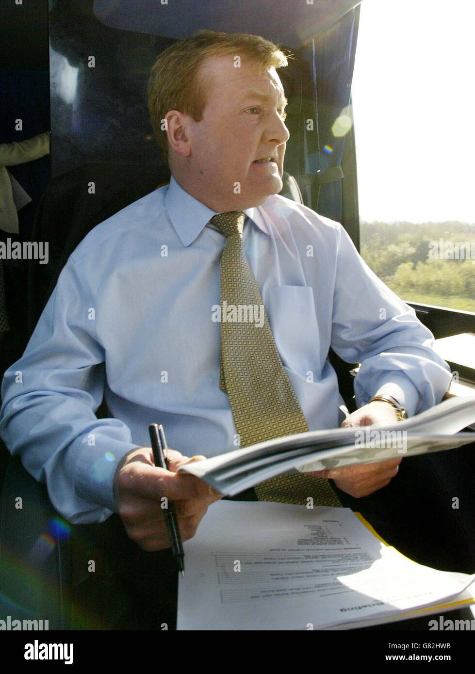 Charles Kennedy étudie les articles sur son autobus de campagne lors d'un voyage à Surrey. Banque D'Images