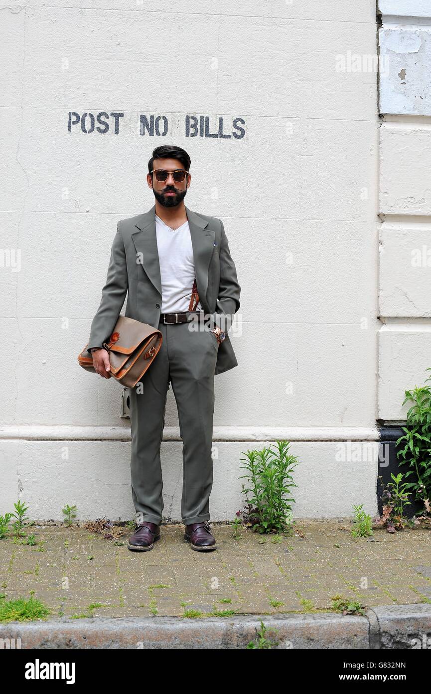Saran Kohli porte sa propre combinaison avec des lunettes de soleil et des  chaussures Topman de Kurt Geiger ainsi qu'un sac Dooney & Bourke devant  l'ancien bureau de triage de Londres lorsqu'il