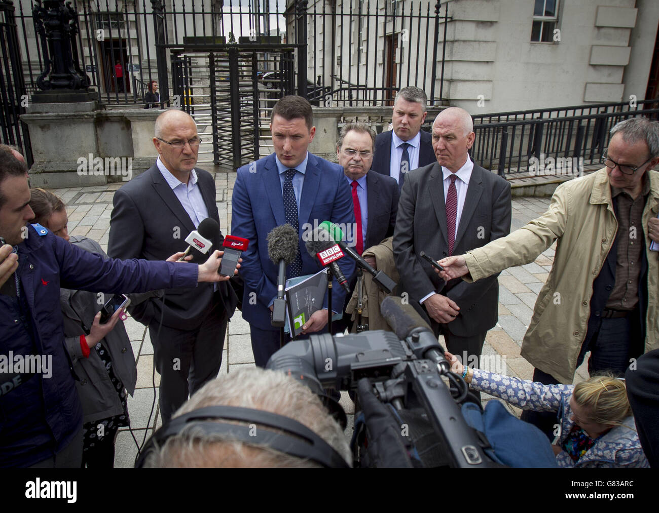 John Finucane, fils de Pat Finucane, avec ses oncles Seamus Finucane (à gauche du groupe) et Martin Finucane (à droite du groupe) avec leur équipe juridique, parle avec les médias en dehors de la haute cour de Belfast, Après que le juge Stephens a décidé que la décision prise par le Premier ministre britannique David Cameron de ne pas tenir d'enquête publique sur le meurtre de son père en 1989 était légale. Banque D'Images