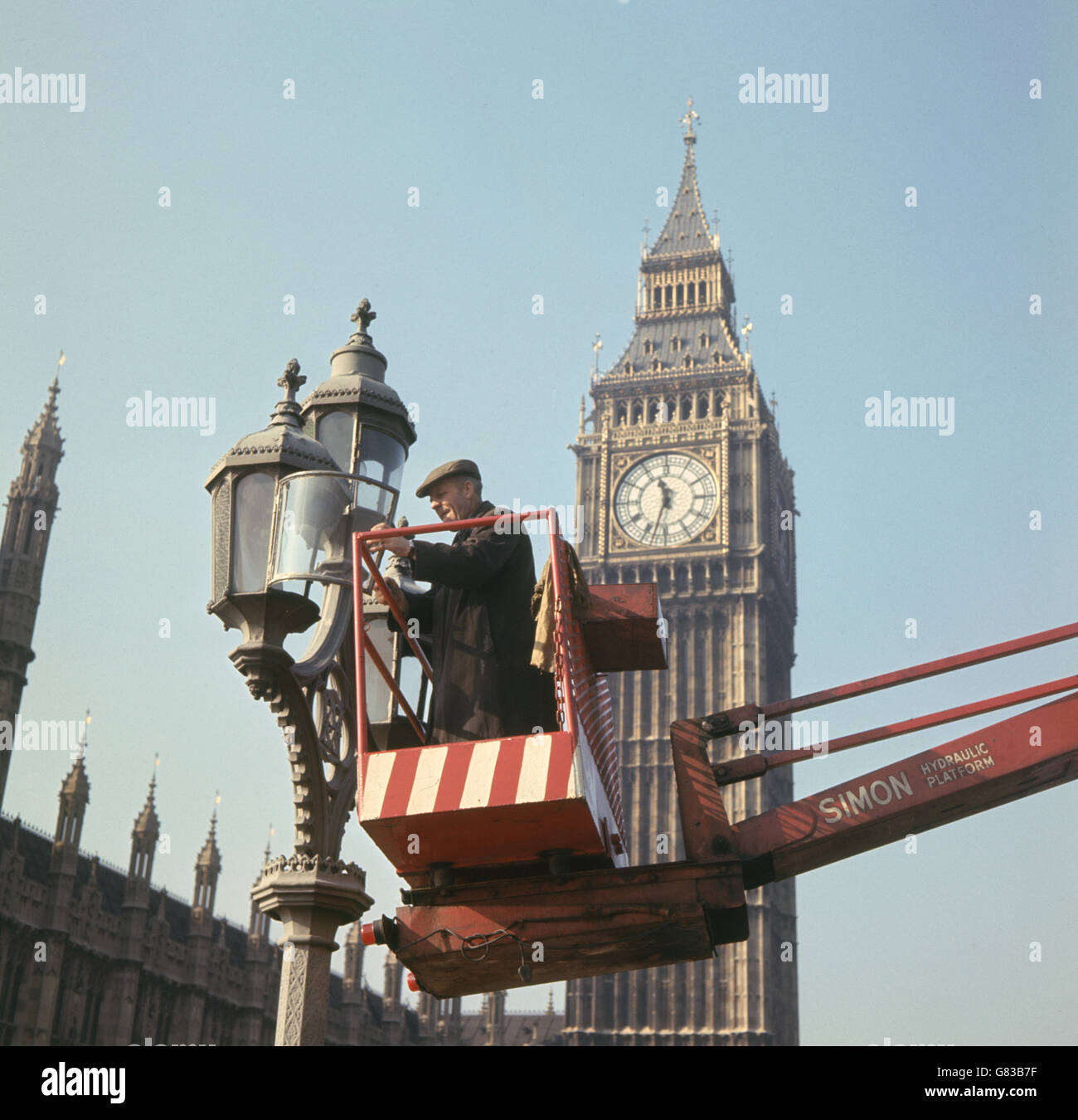 Bâtiments et monuments - Big Ben - Londres.Un ouvrier nettoie les lampes du pont de Westminster, à l'ombre de Big Ben et des chambres du Parlement. Banque D'Images