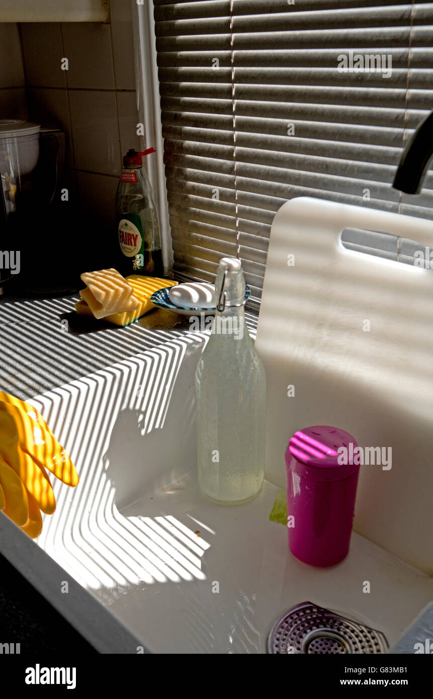 La lumière du soleil tombe en bandes sur un évier de cuisine stores par. Banque D'Images