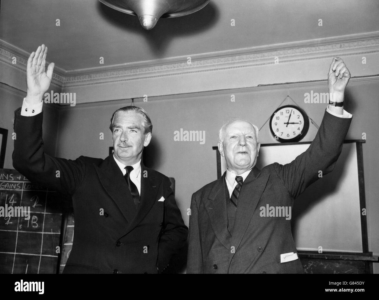 Le premier ministre sir Anthony Eden et Lord Woolton, président du Parti conservateur, lèvent les bras en réponse aux encouragements de leurs collègues du Parti à Abbey House, à Westminster, après le retour au pouvoir des conservateurs aux élections générales. Banque D'Images