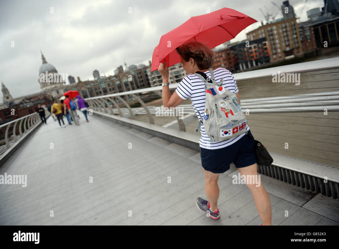 Les gens utilisent des parapluies lorsqu'ils traversent le Millennium Bridge de Londres, par temps humide, alors que le Royaume-Uni semble susceptible d'éviter une malédiction de précipitations prolongées préconnue dans la légende britannique, malgré un début brumeux pour une grande partie du pays, Comme le mythe de la Saint-Sin's Day l'indique si elle pleut le 15 juillet, le temps humide persistera pendant 40 jours et 40 nuits. Banque D'Images