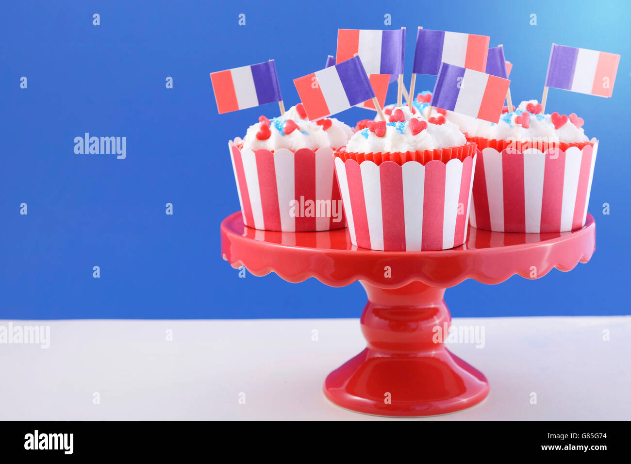 Heureux le jour de la Bastille rouge, blanc et bleu cupcakes sur red cakestand sur fond blanc et bleu. Banque D'Images