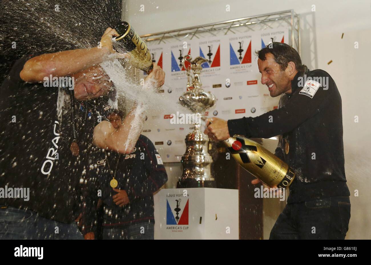 Ben Ainslie (à droite), skipper de l'équipe britannique de LA barre soutenue par Land Rover (Ben Ainslie Racing), vaporise du champagne sur le skipper rival Jimmy Spithill d'Oracle Team USA alors qu'il célèbre la victoire de la coupe britannique de l'America's Cup World Series dans les eaux au large de Portsmouth. Banque D'Images