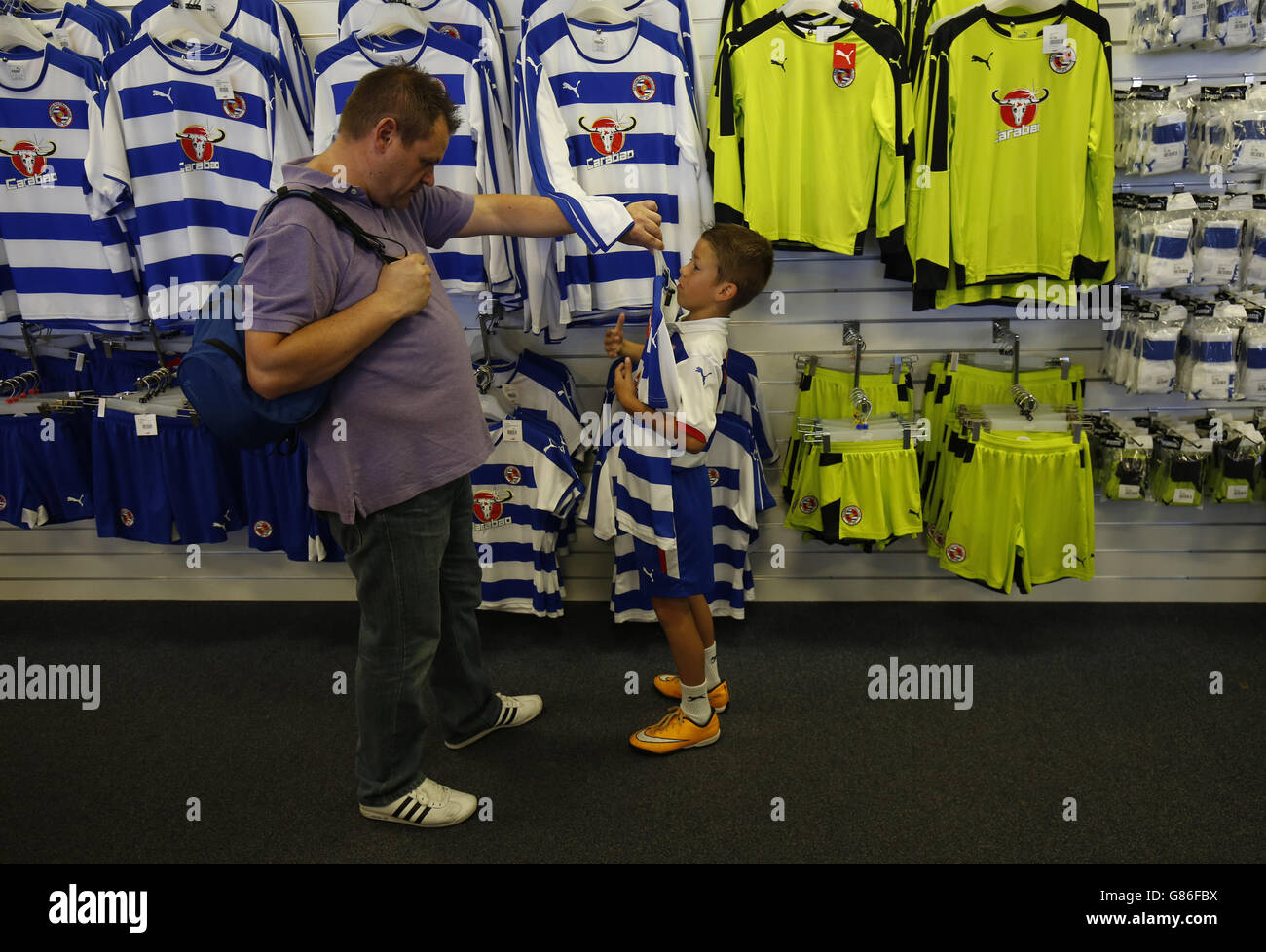 Un jeune fan essaie une chemise dans la boutique du club Avant la correspondance entre lecture et MK dons Banque D'Images