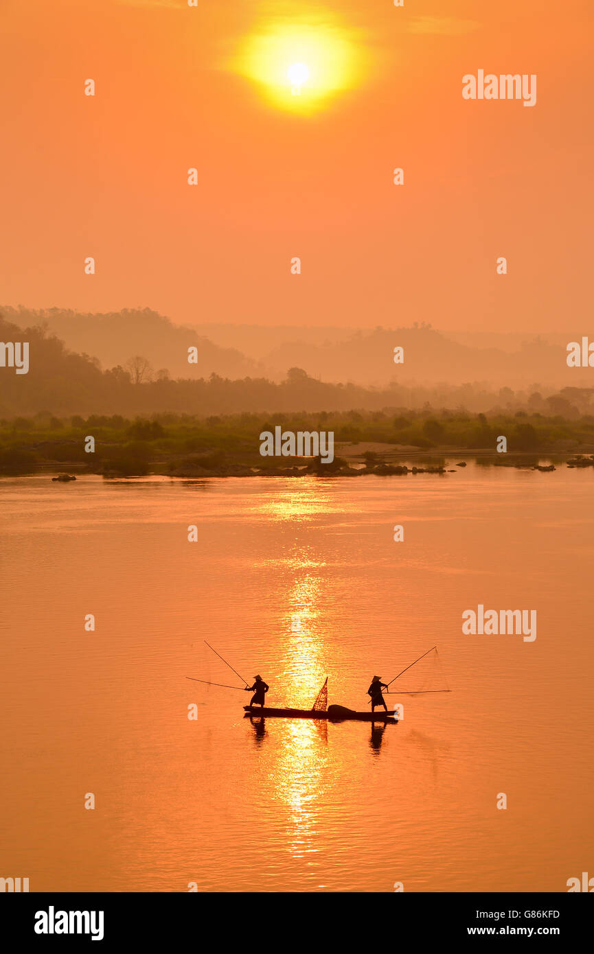 Silhouette de deux pêcheurs en bateau sur le fleuve Mekong, Thaïlande Banque D'Images