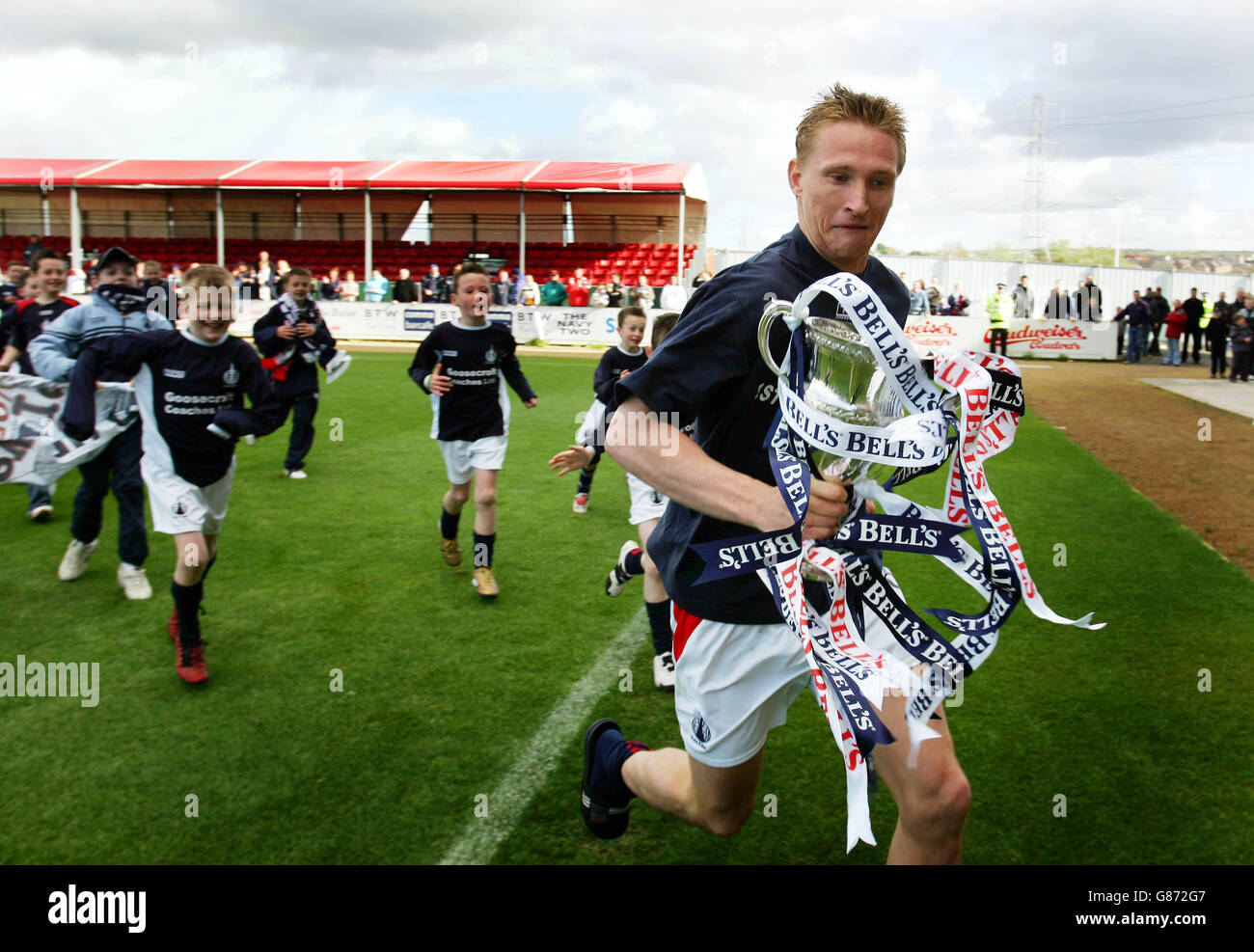 Daniel McBreen de Falkirk est chassé par des membres de la communauté de Falkirk Équipe avec le trophée Scottish football League Frist Division Banque D'Images
