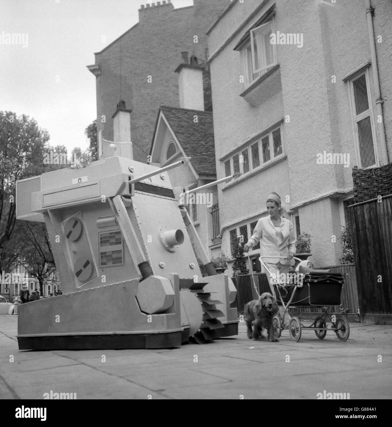 Tilly Hewitt, en passant avec son bébé Dominic, a jeté un regard perplexe sur la grande pièce de machines guerriers de Cornwall Gardens Walk, Kensington, Londres.Le monstre mécanique a été filmé en scènes pour la nouvelle série BBC One 'Doctor Who'. Banque D'Images