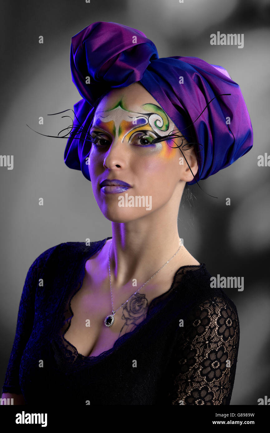 Modèle féminin avec portrait maquillage créatif tribal swirl et turban violet, robe en dentelle noire Banque D'Images