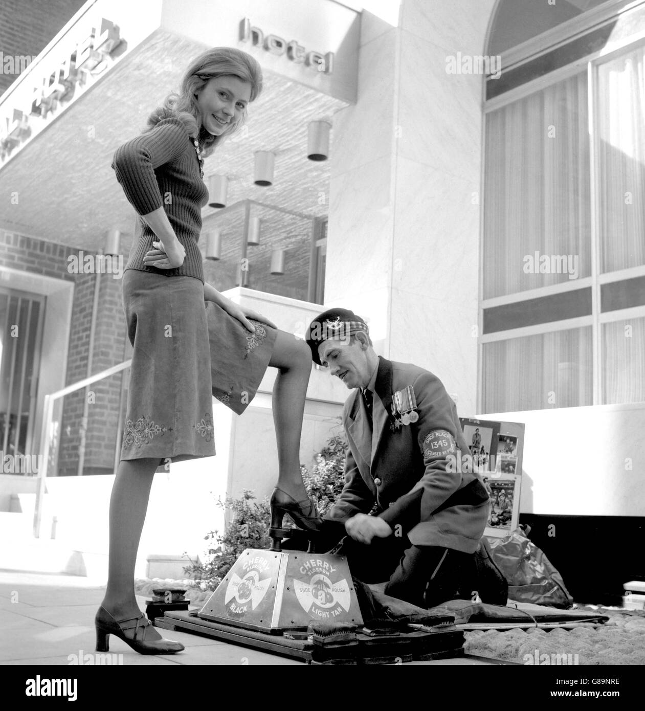 Ann Levin fait nettoyer ses chaussures à l'extérieur du Capital Hotel, Knightsbridge, qui appartient à son mari magnat David Levin.Le shoeshine, connu sous le nom de Jock, est un personnage familier de Piccadilly Circus, mais il a temporairement pris sa place devant l'entrée de l'hôtel. Banque D'Images