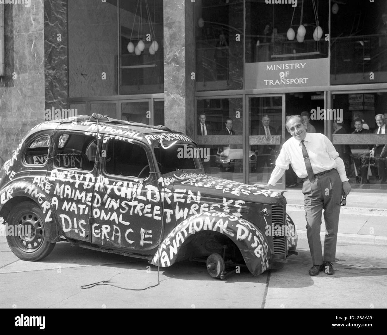 Joseph Mourat, 41 ans, propriétaire d'hôtel de Bickley, Kent, avec la voiture 1948 Austin 10 abandonnée qu'il a apportée pour protester contre l'entrée du ministère des Transports à Southwark Street, Londres. La voiture avait été abandonnée pendant un certain temps devant son hôtel et, parce que les autorités n'ont pris aucune mesure pour la retirer, Mourat a remorqué la voiture à Londres. Banque D'Images